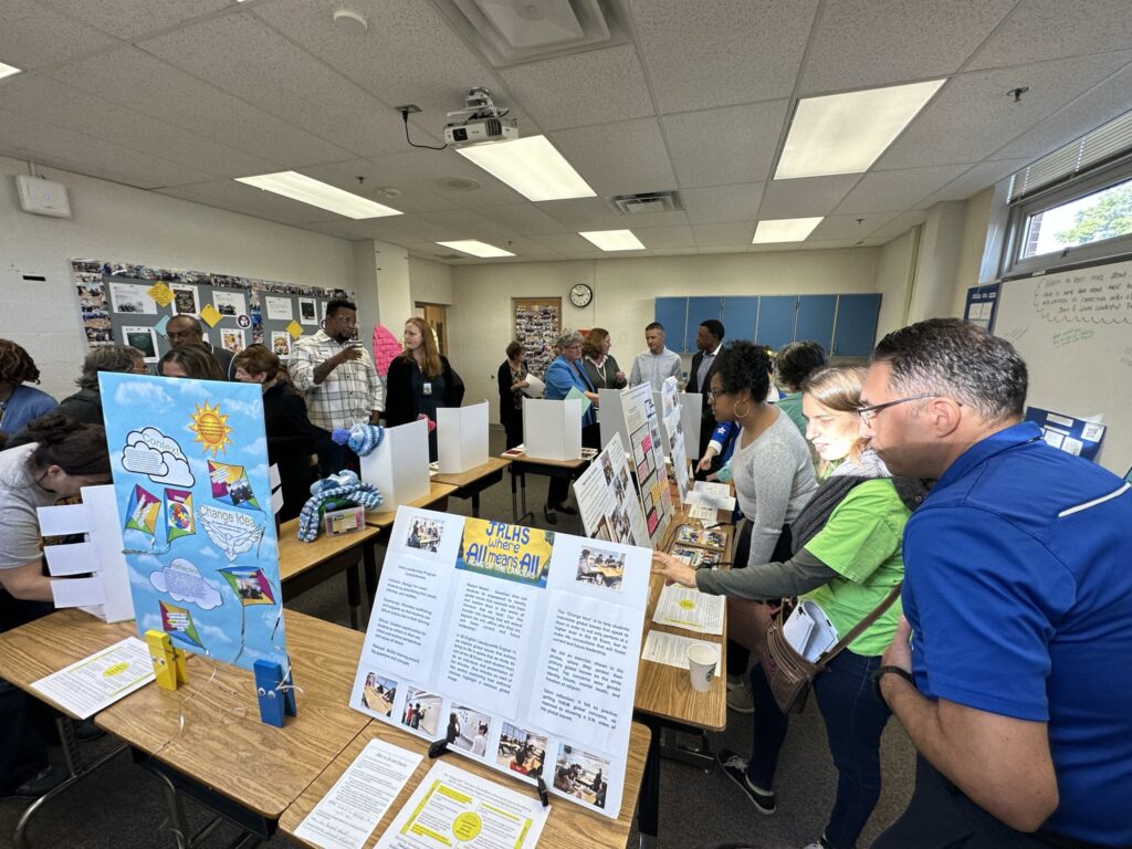 Lewis staff, FCPS staff, and community partners at the exhibition. Teachers looking at poster board presentations around a classroom.