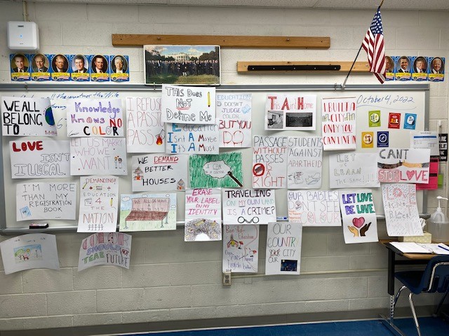 A wall in a classroom is covered in student-made protest signs.