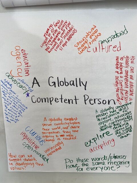 A large sheet of paper with ideas and questions written by teachers, centered on the phrase "A Globally Competent Person." (3 of 3)