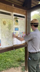 A park ranger posts hand-made signs made by students.